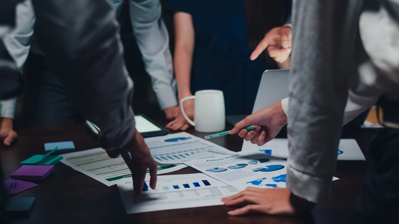 A group of people standing around a table with papers.